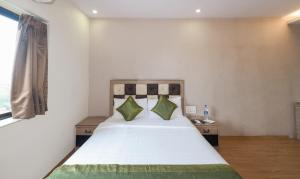 贾姆谢德布尔Treebo Trend Pal Comfort的卧室配有带绿色枕头的大型白色床