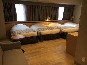 福冈福冈蒙特埃马纳酒店的酒店客房设有三张床和一张桌子