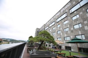 晋州市Hotel Dongbang的河边的一座带桌子和遮阳伞的建筑