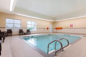 鲍曼维尔Comfort Inn & Suites的一个带椅子和桌子的房间的游泳池