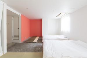 金泽Crasco TABI-NE的一间卧室设有两张床和红色的墙壁