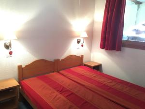 莱德萨阿尔卑斯T3 Les deux Alpes Vallée Blanche的一间卧室配有一张带红色床单的床和两盏灯。