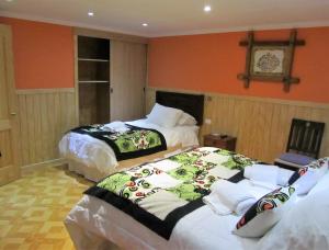 纳塔列斯港Patagonia Swiss House的橙色墙壁客房的两张床