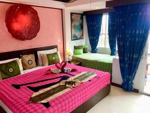 卡塔海滩玛尔之家旅馆的一间卧室配有粉色和绿色的床及带丝带