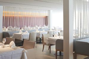 博登斯边的拉多夫采尔博拉温泉Spa度假酒店的餐厅设有白色的桌椅和大窗户