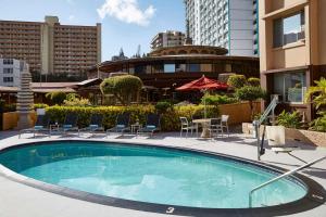 檀香山帕戈达酒店的一座带桌椅的游泳池以及大楼