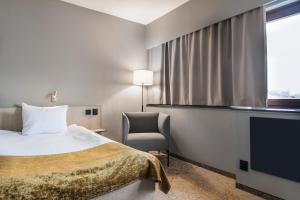 韦克舍皇家之角品质酒店的酒店客房配有一张床、一把椅子和一台电视。