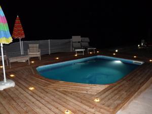 潘泰莱里亚Dammuso Kania alta的夜间游泳池,设有木甲板