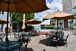 瓜达拉哈拉乡村酒店及套房的户外庭院配有桌椅和遮阳伞。