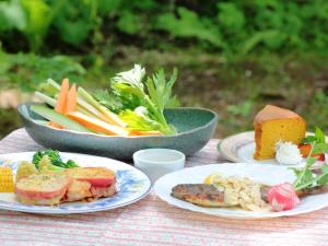 原村Pension Peppermint House的餐桌,盘子上放着食物和蔬菜碗