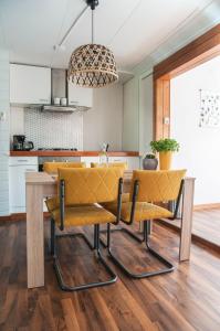 斯塔福伦Heerlijk Huis aan het IJsselmeer的厨房配有带黄椅的餐桌