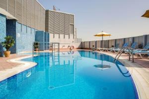迪拜Pearl Executive Hotel Apartments的一个带椅子和遮阳伞的大型蓝色游泳池