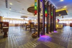 迪拜Pearl Executive Hotel Apartments的餐厅设有桌椅和色彩缤纷的灯光