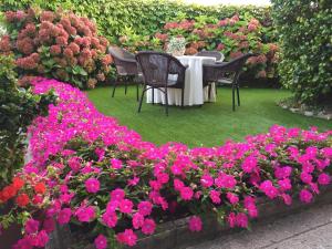 库迪列罗卡瑟纳贝尼托乡村民宿的花园里的桌椅和粉红色的鲜花