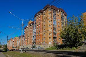 托木斯克Apart Petrovskie on Sovetskaya 60的一座大型砖砌建筑,前面有汽车停放