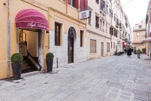 威尼斯阿格里阿迪斯提酒店的一条空的街道,在一座建筑物上遮着紫色的遮篷