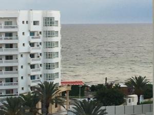 苏塞Sousse Corniche Taib Mhiri Roadin Front of Riadh Palm Hotel的毗邻大海的白色大建筑