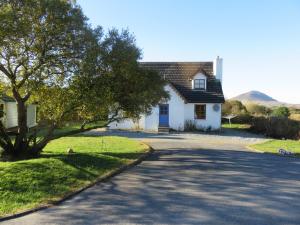 莱特弗拉克Letterfrack Farm Cottage in village on a farm beside Connemara National Park的白色的房子,有树和路