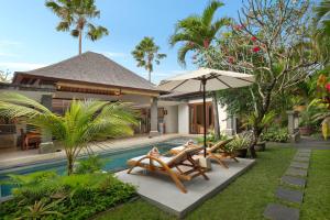 塞米亚克布阿巴厘岛别墅酒店的一座房子旁的游泳池,配有两把椅子和一把遮阳伞