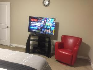 温尼伯Beautiful and Safe Home的一间带电视和红色椅子的卧室