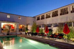 圣马迪拉莫维拉德拉玛尔Spa酒店的一座带红伞的建筑前的游泳池