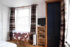 伦敦加勒多念一室公寓的一间卧室配有一张床、一张桌子和一台电视。