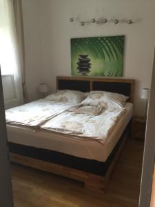 Fernitz费迪南德公寓的一张铺有白色床单的床和墙上的绿色画作