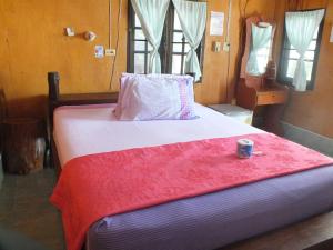 涛岛皇后龟岛度假酒店的一张带红毯的床,上面有一杯