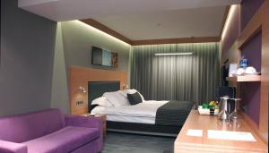 伊兹密尔迈特精品酒店的酒店客房设有一张床和一张紫色沙发