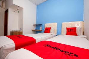 三宝垄RedDoorz Near Kota Lama Semarang的宿舍间内的两张床,配有红色枕头