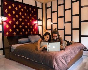 曼谷萨瓦迪原始旅舍 的男人和女人躺在床上,手提电脑