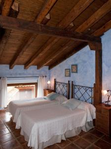 Villalón de CamposCasa Rural El Encuentro的卧室设有两张床,拥有蓝色的墙壁和木制天花板