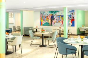 迪拜Queen Elizabeth 2 Hotel的餐厅设有桌椅,墙上挂有绘画作品