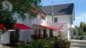 贝尔吉施格拉德巴赫Hotel Boskamp的白色的建筑,上面有红色遮阳篷