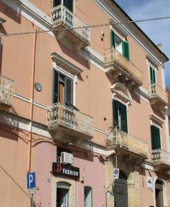 卡斯泰拉内塔B&B Palazzo Rochira的粉红色的建筑,设有阳台和标志
