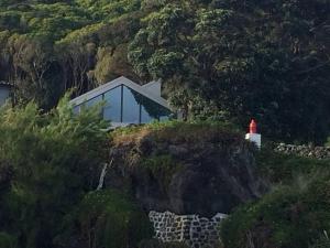 Calheta de NesquimT2 Lux Casa das Pereiras的悬崖上一座有红灯塔的房子