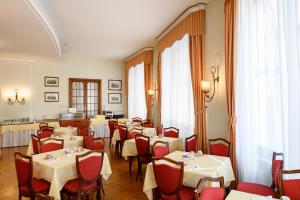 特雷维索欧陆酒店的用餐室配有桌子和红色椅子