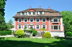 温特图尔Villa Jakobsbrunnen的一座红色和白色的大房子,有院子