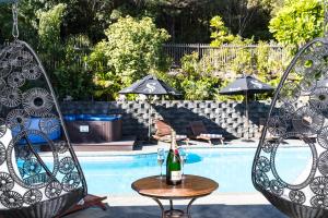 帕瓦努伊美爵普卡园度假酒店的游泳池畔的两把椅子和一张桌子及一瓶香槟