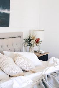 班加洛班加洛宾馆的一张带枕头的白色床和一张花瓶桌子