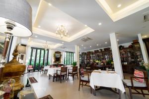 清迈Villa Klang Wiang的餐厅设有白色的桌椅和窗户。