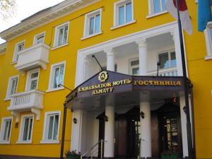 阿拉木图大使酒店的黄色的建筑,前面有标志