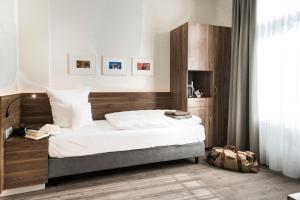 明斯特Alexianer Hotel am Wasserturm的一间卧室配有一张大床和木制床头板