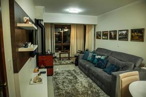 格拉玛多Ednamar Apartmentos Gramado Siena的客厅配有灰色的沙发和蓝色的枕头。