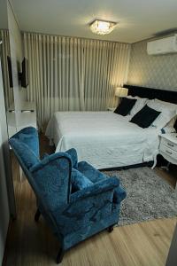 格拉玛多Ednamar Apartmentos Gramado Siena的一间卧室配有一张床和一张蓝色椅子