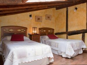 Villalón de CamposCasa Rural El Encuentro的一间卧室配有两张带白色床单和红色枕头的床。