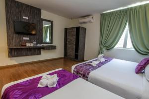 珍南海滩Salsa Resort Langkawi By Casa Loma的客房设有两张带紫色床单的床和一台电视。