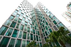 吉隆坡Soho Suites KLCC的一座高大的玻璃建筑,前面有棕榈树