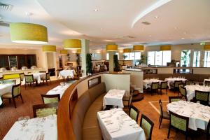 查尔维尔Charleville Park Hotel & Leisure Club IRELAND的一间设有白色桌椅的餐厅和一间酒吧