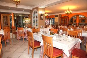 El AlquiánHotel Los Arcos的餐厅配有桌椅和白色的桌布